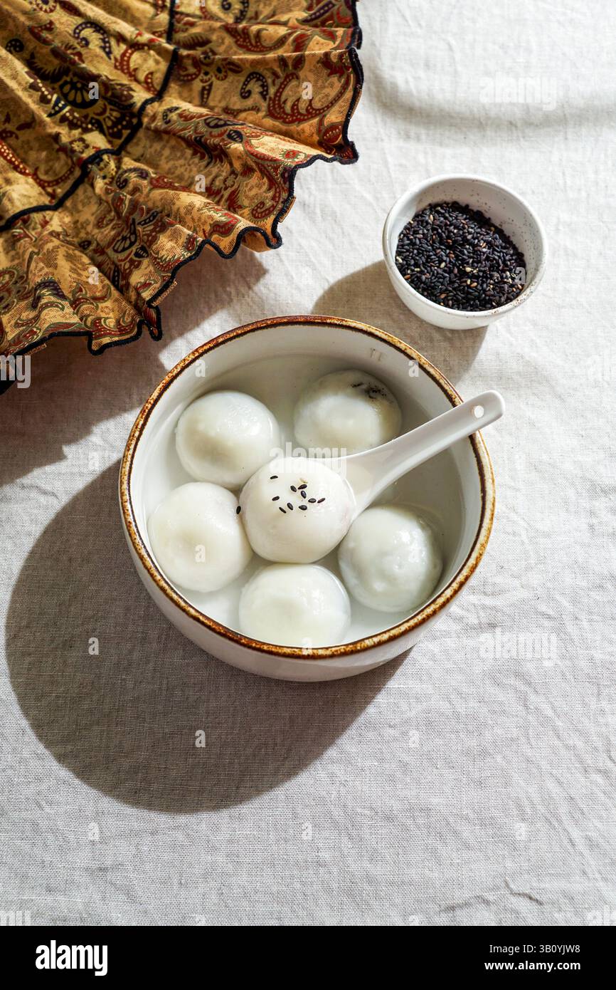 Tang Yuan, dessert asiatique traditionnel composé de boulettes de riz glutinus au sirop sucré, servi dans un bol avec une cuillère. Banque D'Images