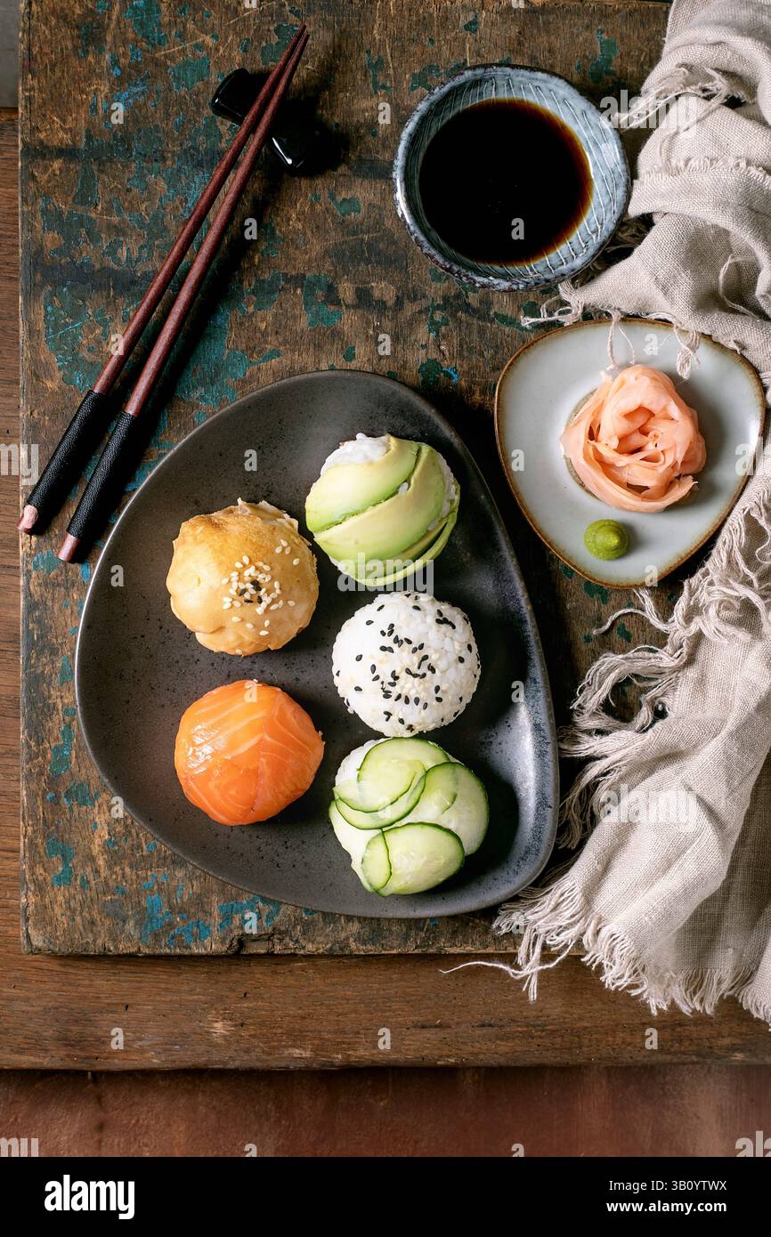 Temari sushi. Boules de sushi tendance avec saumon, avocat, concombre et omelette japonaise sur plaque de céramique brune. Sauce soja, gingembre mariné, baguettes, Li Banque D'Images