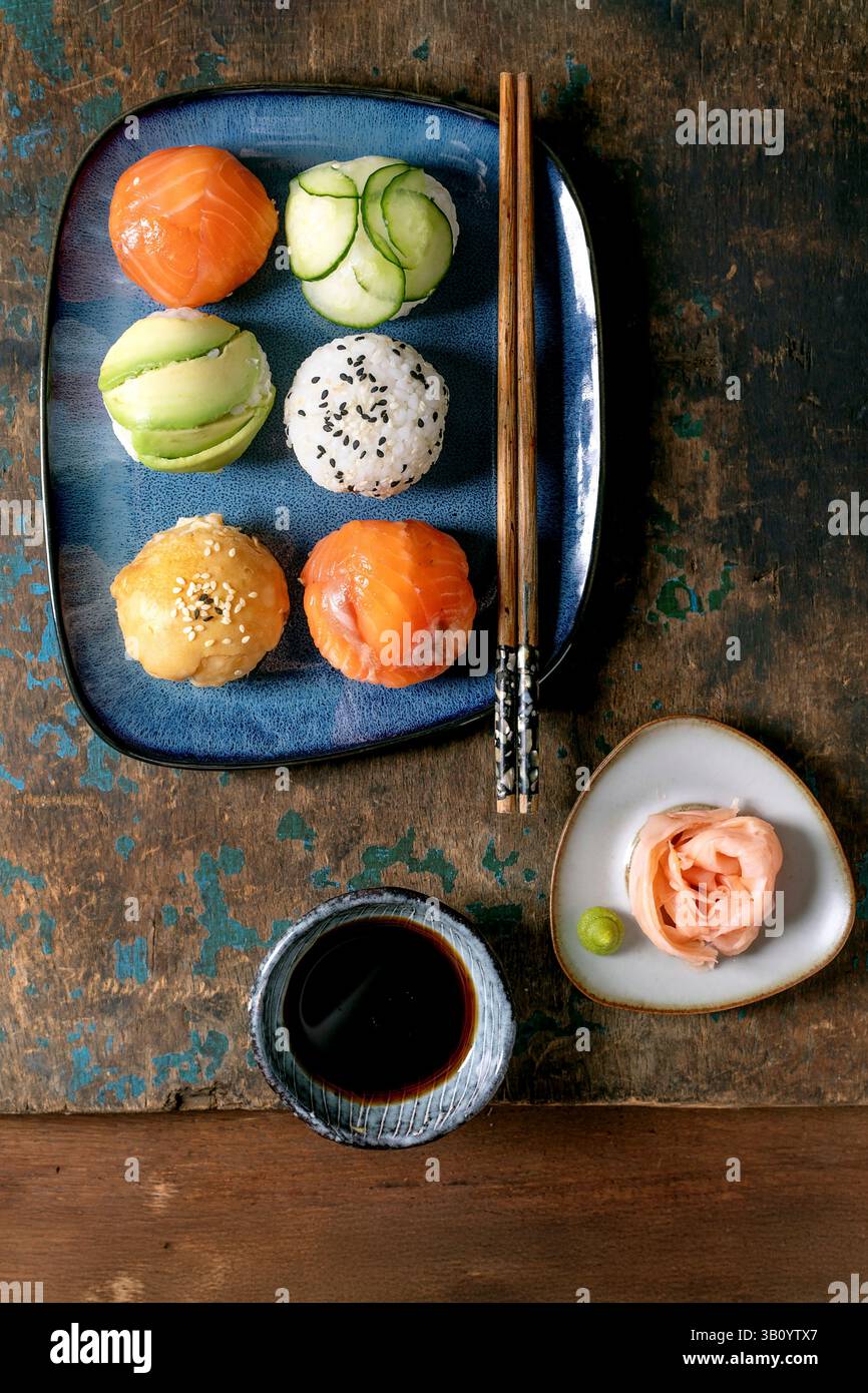 Temari sushi. Boules de sushi tendance avec saumon, avocat, concombre et omelette japonaise sur assiette bleue. Sauce soja, gingembre mariné, baguettes sur WO rustique Banque D'Images