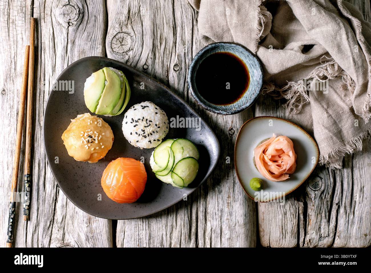 Temari sushi. Boules de sushi tendance avec saumon, avocat, concombre et omelette japonaise sur plaque de céramique brune. Sauce soja, gingembre mariné, baguettes, Li Banque D'Images