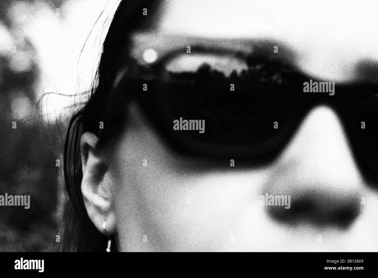 Une femme portant des lunettes de soleil, un portrait en noir et blanc avec le reflet de la nature. Un gros plan noir et blanc met en valeur le visage d'une femme. Banque D'Images