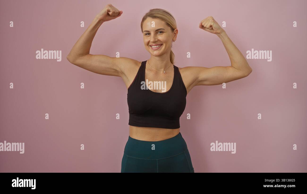 Femme fléchissant les muscles en toute confiance sur fond rose isolé, mettant en valeur la force et la forme physique dans un style moderne, attrayant et jeune, perfec Banque D'Images