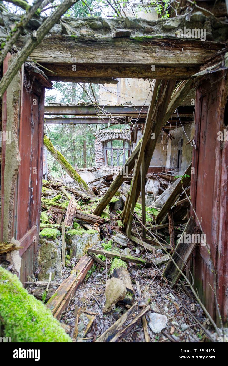 Bad Illstern, italie., lieu perdu. Vue intérieure d'un bâtiment délabré avec toit effondré et plancher rempli de gravats, vu à travers une porte ouverte Banque D'Images