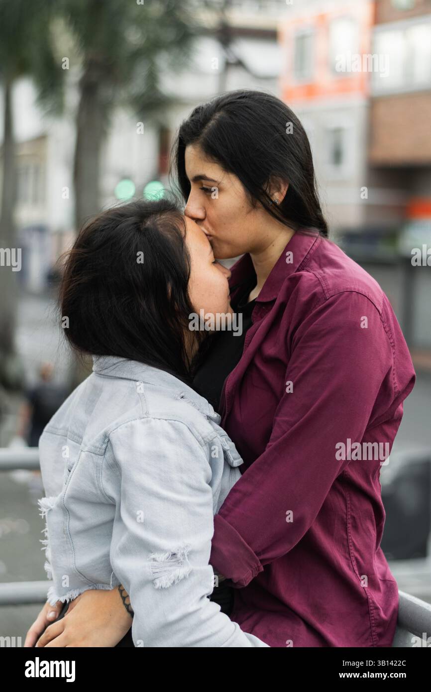jeune couple lesbien latina serrant dans la rue tandis que l'un d'eux embrasse le front de sa petite amie Banque D'Images