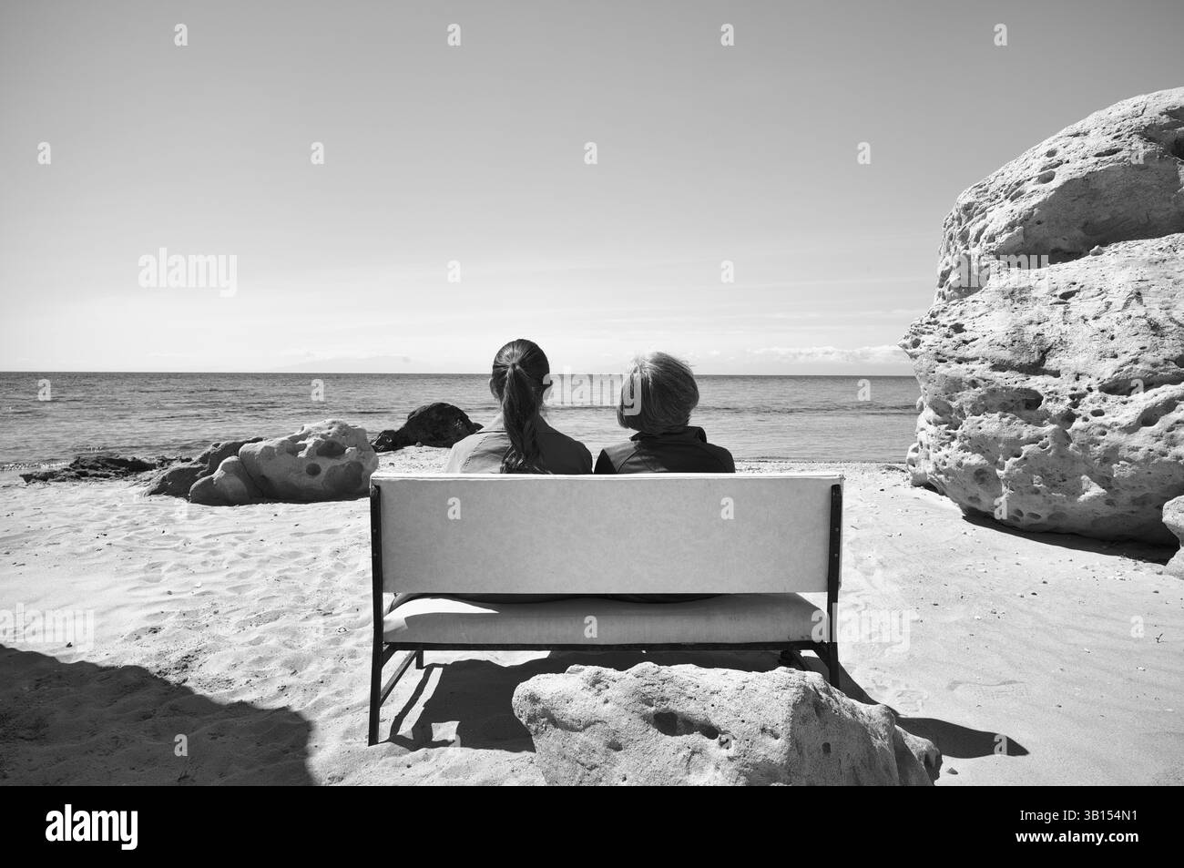 Deux femmes assises sur un banc, rochers sur la plage de Nea Kallikratia, Chalcidique, Macédoine, noir et blanc, Grèce, Europe Banque D'Images