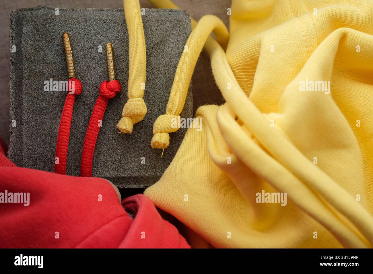 Détails capuche cordons de serrage. Les cordons de serrage rouge vif ont des embouts en métal de couleur or. Extrémités jaunes tendres nouées. Banque D'Images