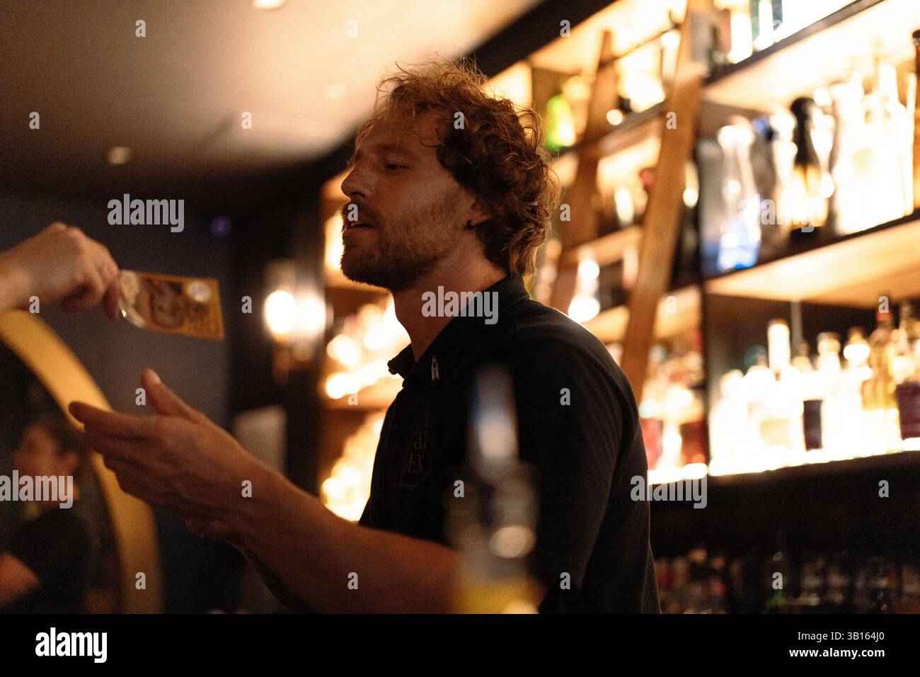 Le barman d'un bar de nuit tient de l'argent dans ses mains Banque D'Images
