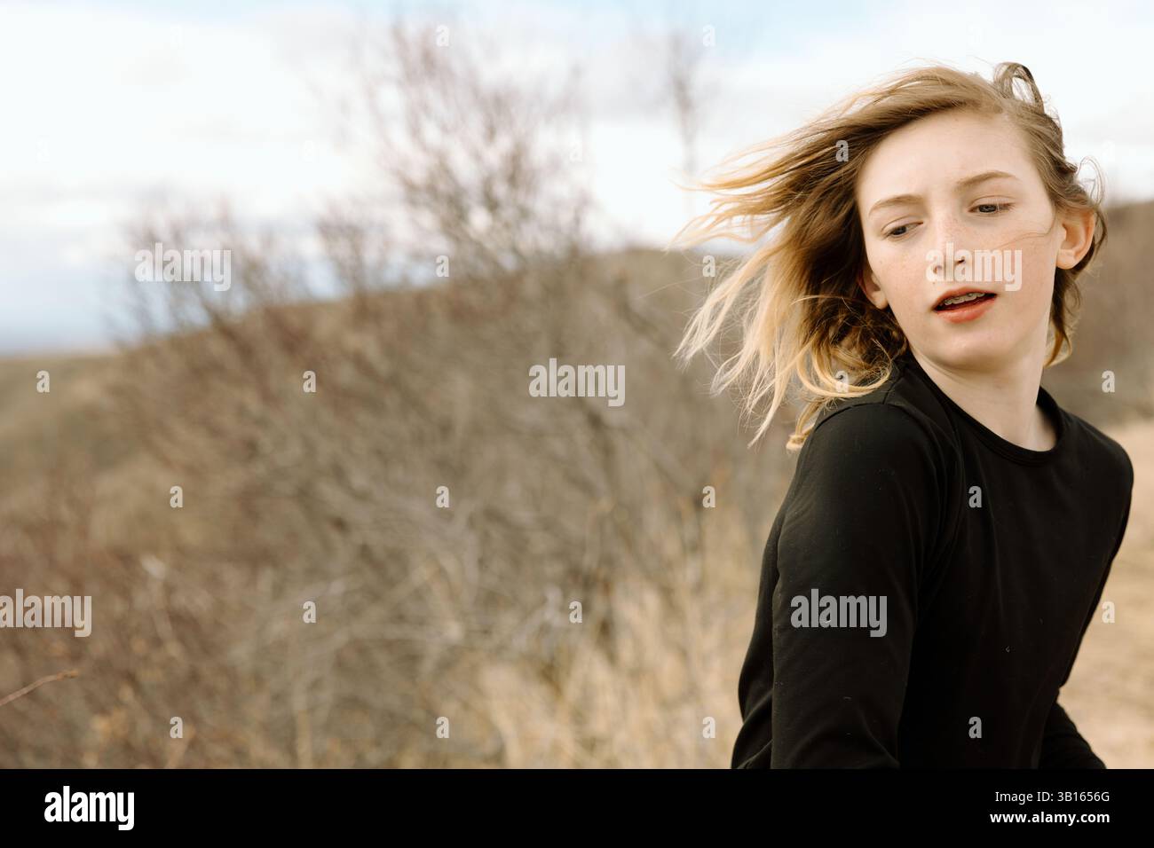 Adolescent jetant un coup d'œil en arrière tout en faisant une randonnée sur un sentier à flanc de colline Banque D'Images