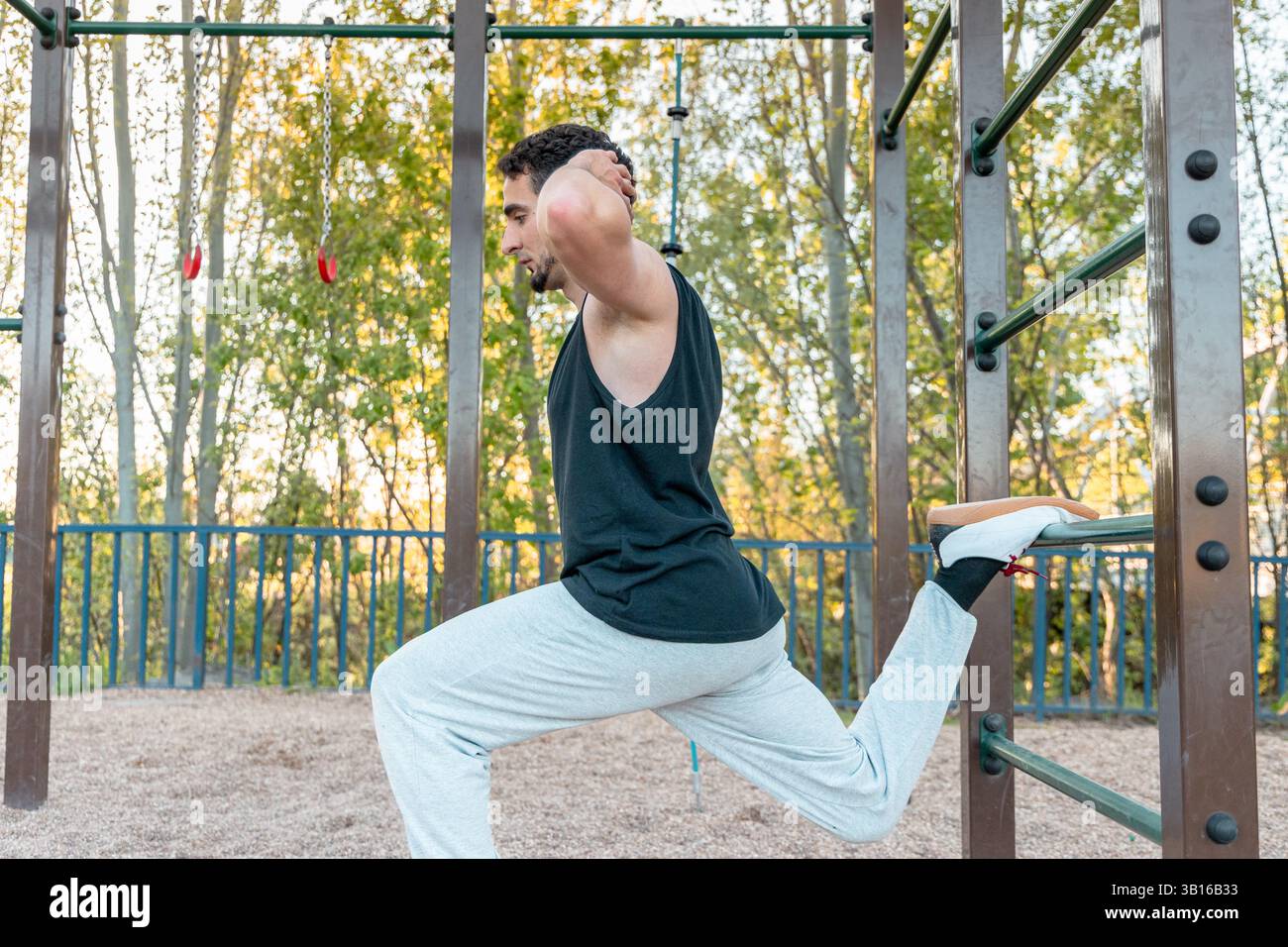 Homme s'étirant en position de squat fractionné bulgare avec pied arrière surélevé sur la barre, améliorant la flexibilité, l'équilibre et la mobilité des hanches à l'extérieur Banque D'Images