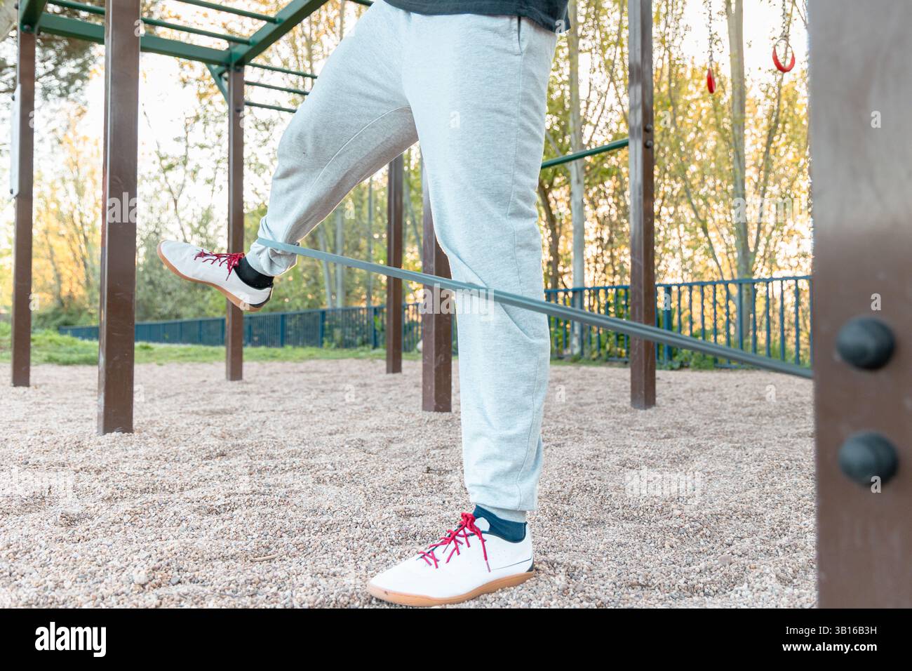 Exercice d'échauffement de bande de résistance du bas corps effectué par l'homme dans le parc de calisthenics extérieur, ciblant la mobilité de la hanche, la stabilité et l'activation des jambes Banque D'Images