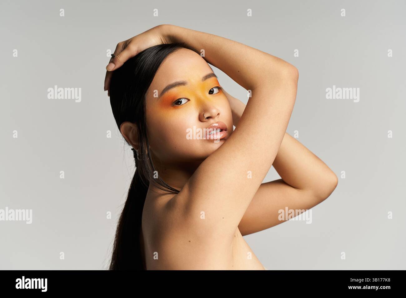 Jeune belle femme présente un maquillage artistique avec des couleurs audacieuses, posant gracieusement dans un studio. Banque D'Images