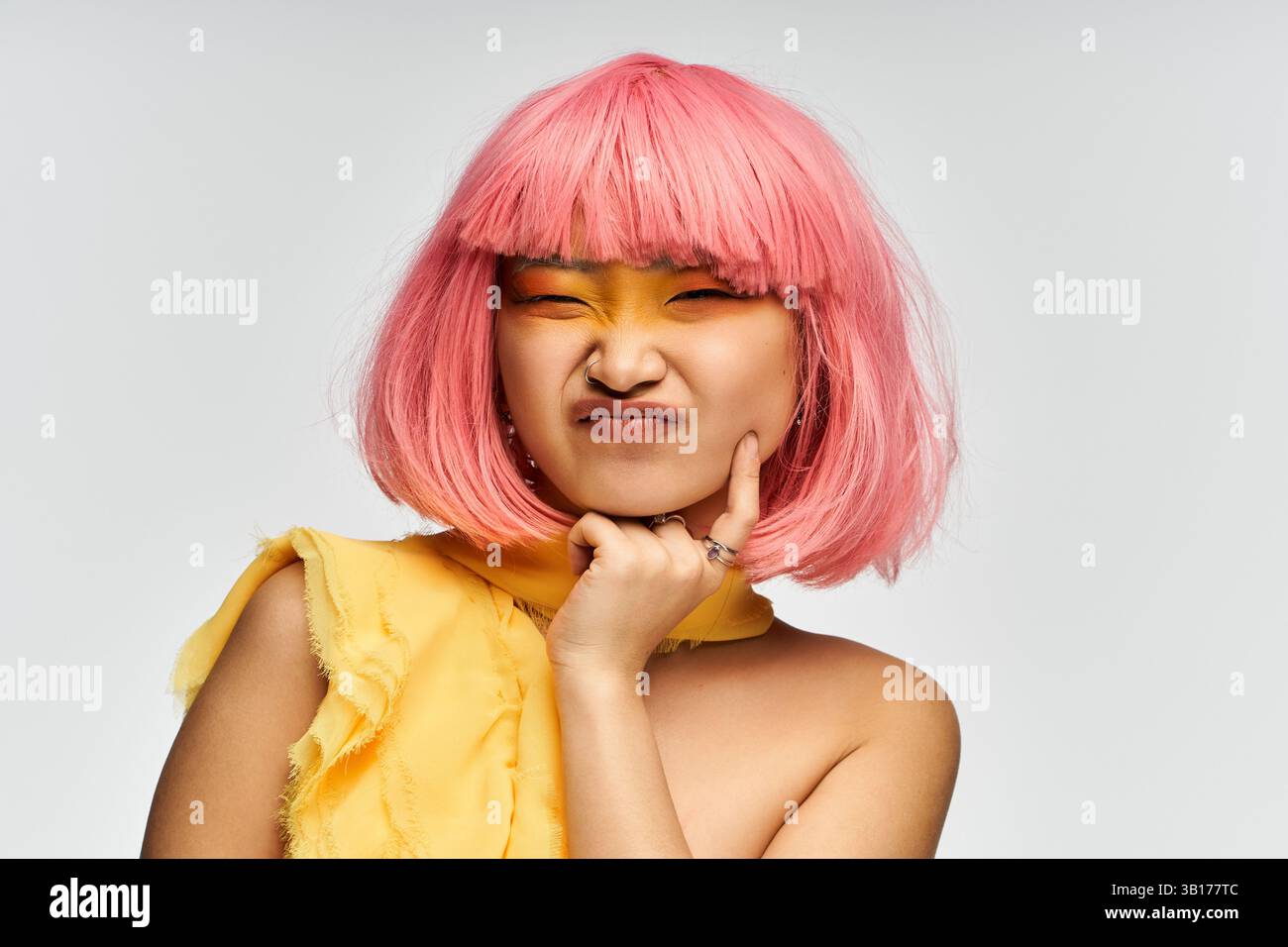Jeune femme asiatique avec des cheveux roses vibrants et des poses de maquillage audacieux. Banque D'Images