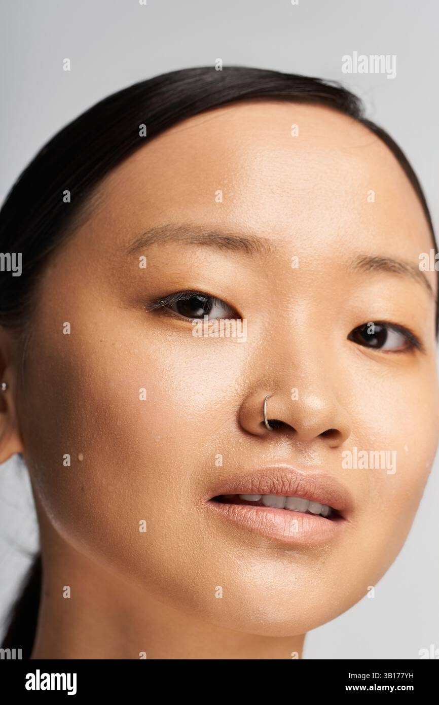 Jeune femme asiatique rayonnante à la peau impeccable sourit gracieusement tout en mettant en valeur sa beauté. Banque D'Images