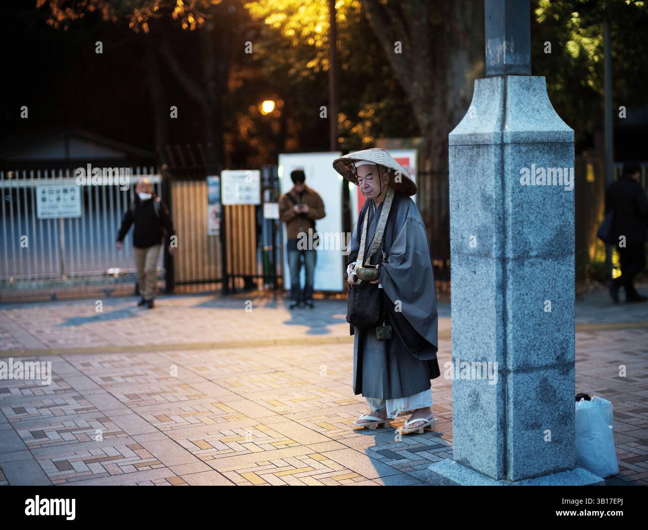 Moine bouddhiste japonais en robes traditionnelles debout sur la rue de la ville au crépuscule à Tokyo Banque D'Images