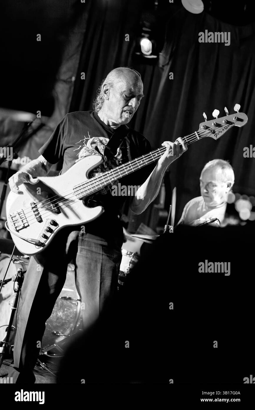 Norman Watt-Roy joue sa basse avec passion sur scène, illuminé par des projecteurs dans un sombre et atmosphérique Half Moon, Putney. Banque D'Images