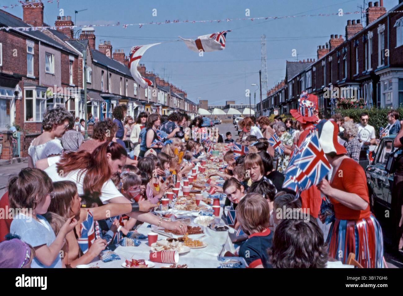 Tout au long du Royaume-Uni, des fêtes de rue célébrant le mariage du prince Charles (futur roi Charles III) et de Lady Diana Spencer, qui a eu lieu à la cathédrale Saint-Paul de Londres le mercredi 29 juillet 1981. Il y avait une fête nationale ce jour-là pour marquer le mariage. Ici, un déjeuner en plein air pour enfants a été préparé, avec des boissons gazeuses, de la nourriture pour les doigts et des sacs de chips Walkers. Des drapeaux de l'Union Jack en plastique sont distribués et des drapeaux blancs et des banderoles flottent dans la brise. Banque D'Images