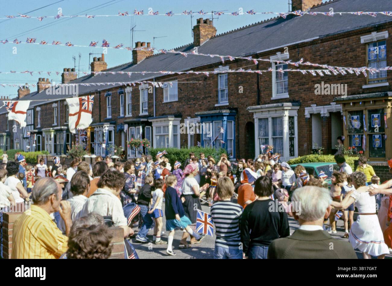Tout au long du Royaume-Uni, des fêtes de rue célébrant le mariage du prince Charles (futur roi Charles III) et de Lady Diana Spencer, qui a eu lieu à la cathédrale Saint-Paul de Londres le mercredi 29 juillet 1981. Il y avait une fête nationale ce jour-là pour marquer le mariage. Ici, les enfants et les adultes dansent dans la rue. Les drapeaux et chapeaux de l'Union jack sont exposés et les drapeaux et banderoles blancs flottent dans la brise. Banque D'Images