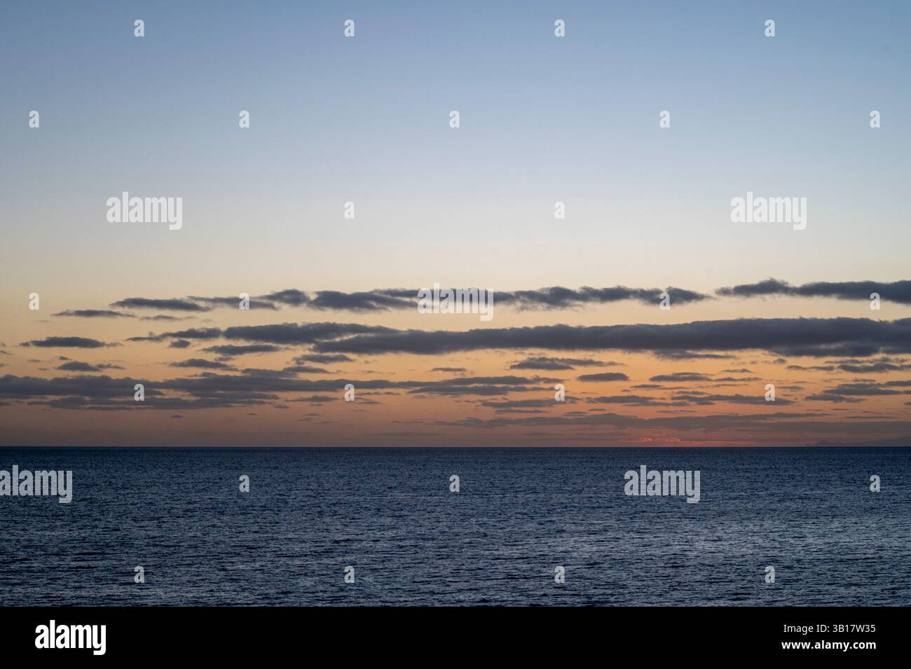 Le ciel est une belle nuance de bleu avec quelques nuages dispersés partout. L'océan est calme et paisible, sans aucun signe d'activité Banque D'Images