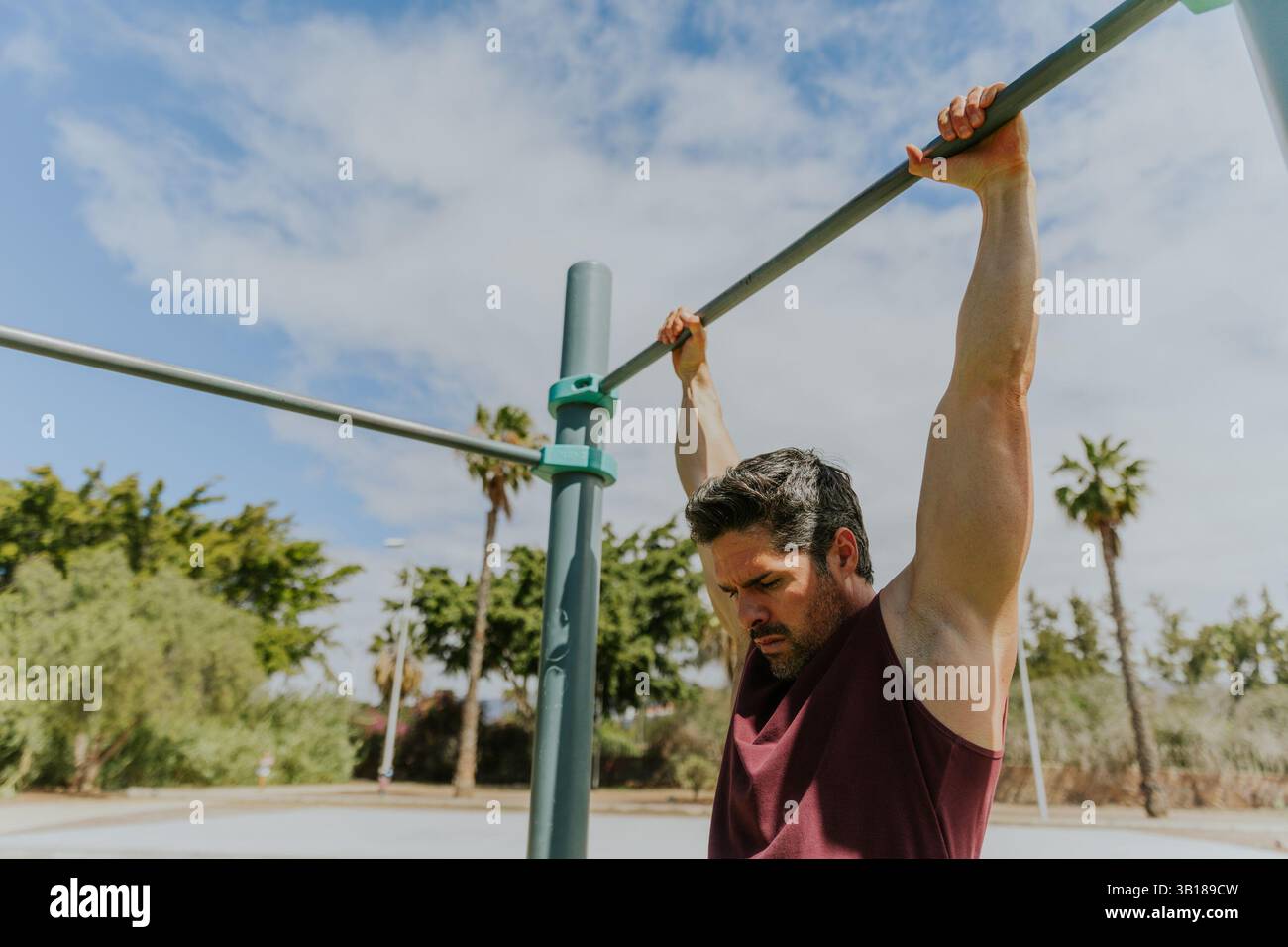 Un homme tient une barre haute dans un gymnase calisthenics pendant une séance d'entraînement prêt à faire des pull ups. Banque D'Images