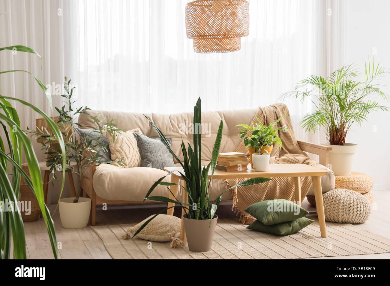 Intérieur de salon lumineux avec canapé beige, table et plantes vertes Banque D'Images