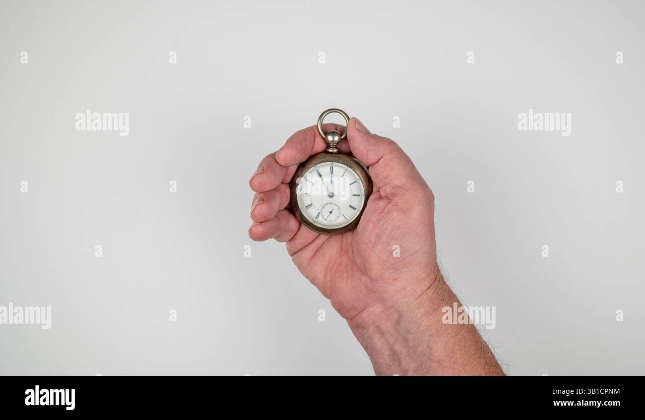 Main masculine caucasienne tenant la montre du conducteur de chemin de fer antique sur fond blanc Banque D'Images