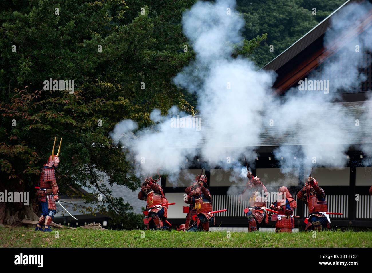 Groupe de guerriers samouraïs du clan II en costume tirant des mousquets vintage menés par un commandant avec une épée lors d'une manifestation de festival à Hikone, au Japon. Banque D'Images