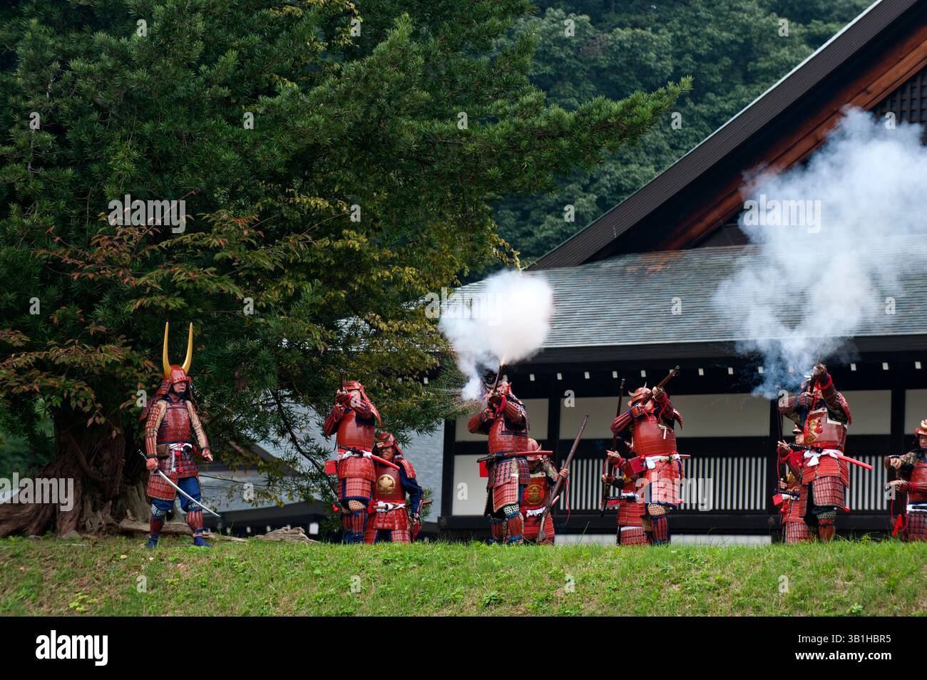 Groupe de guerriers samouraïs du clan II en costume tirant des mousquets vintage menés par un commandant avec une épée lors d'une manifestation de festival à Hikone, au Japon. Banque D'Images