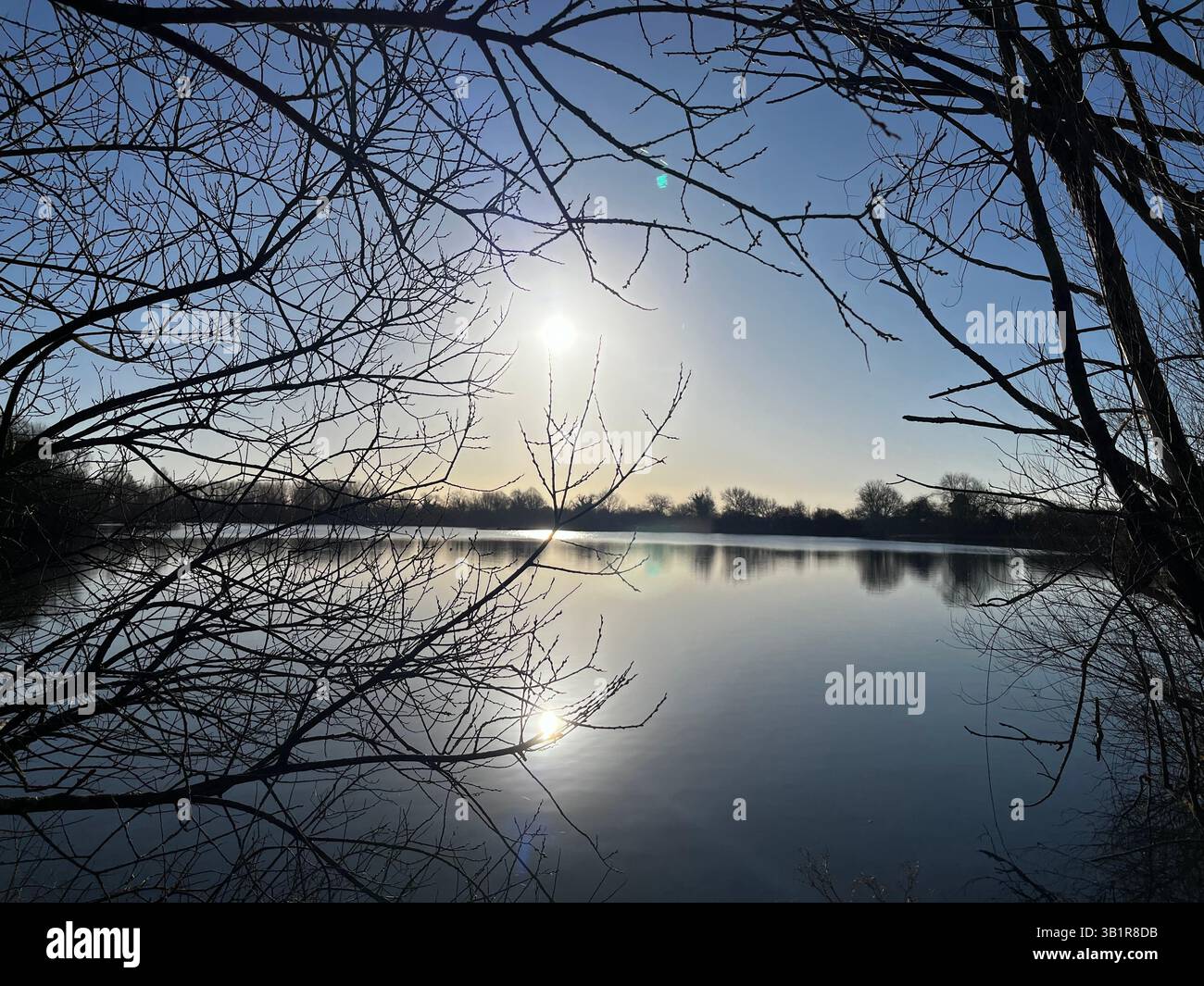 Lac Cotswold dans le matin d'hiver. Beau reflet du soleil et encadré par des arbres. Superbe exemple de la magie des Cotswolds. - Image de stock capturée avec un smartphone