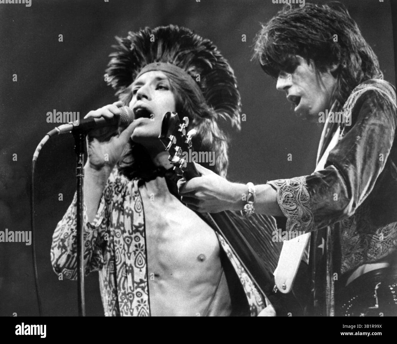 4 juillet 1975 - Memphis, TN, États-Unis - les Rolling Stones au Memorial Stadium (maintenant Liberty Bowl ) à Memphis le 4 juillet 1975. Mick Jagger (à gauche) Keith Richards sont photographiés. L'événement d'une journée comprenait des performances du Charles Daniels Band, du Meters et de la légende du blues Furry Lewis. ''Mick Jagger, vêtu d'un body à motifs rouge et blanc et d'une cape violette, a sombré légèrement sous un parasol'', a écrit Walter Dawson. ''il y avait eu une certaine inquiétude dans le camp des Stones... qu'ils pourraient être arrêtés pour obscénité s'ils utilisaient leur ballon en forme de phallique et effectuaient un petit nombre qui va sous l'alia Banque D'Images