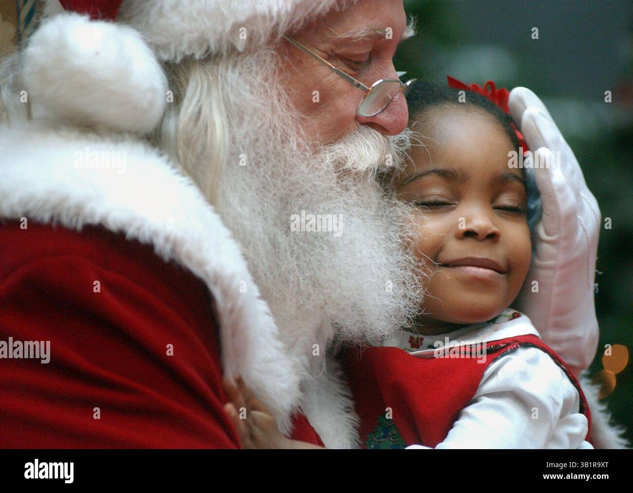 Dec. 23, 2002 - Memphis, TN, États-Unis - 23 DEC 02 (KPSANTA) par Karen Pulfer Focht : Affiong Enyenihi, 2 ans, de Collierville, ferme les yeux dans la joie et se blottit dans l'étreinte du Père Noël lundi à Wolfchase Galleria, sa première visite avec le joyeux vieux elfe. Face au bonheur de Noël, tous les préparatifs et les longues files d'attente semblent soudainement utiles. Ses parents, Rose et Henry, sont tous deux originaires du Nigeria. Ils se sont rencontrés alors qu'Henry, maintenant médecin au Centre de développement d'Arlington, était en mission médicale dans son pays natal. Après avoir déménagé à Memphis en 1997, ils se sont mariés. (Crédit Imag Banque D'Images