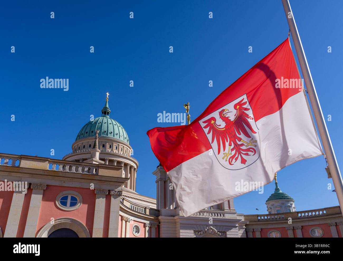 Potsdam, Allemagne. 26 avril 2025. Le drapeau de l'État de Brandebourg flotte en Berne dans la cour intérieure du bâtiment du parlement de l'État sur la toile de fond de l'église Nicolas sur l'Alter Markt. En raison de la mort du pape François et du deuil national associé, des drapeaux de deuil ont également été commandés pour les bâtiments officiels du Brandebourg aujourd'hui. Crédit : Soeren Stache/dpa/Alamy Live News Banque D'Images