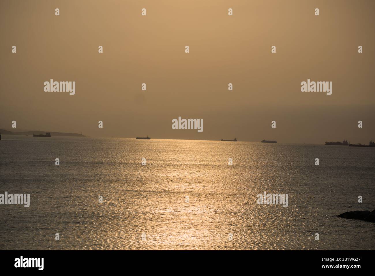Des navires se sont silhouettés à l'horizon lors d'un coucher de soleil doré sur les eaux calmes de l'océan. Salou, Espagne Banque D'Images