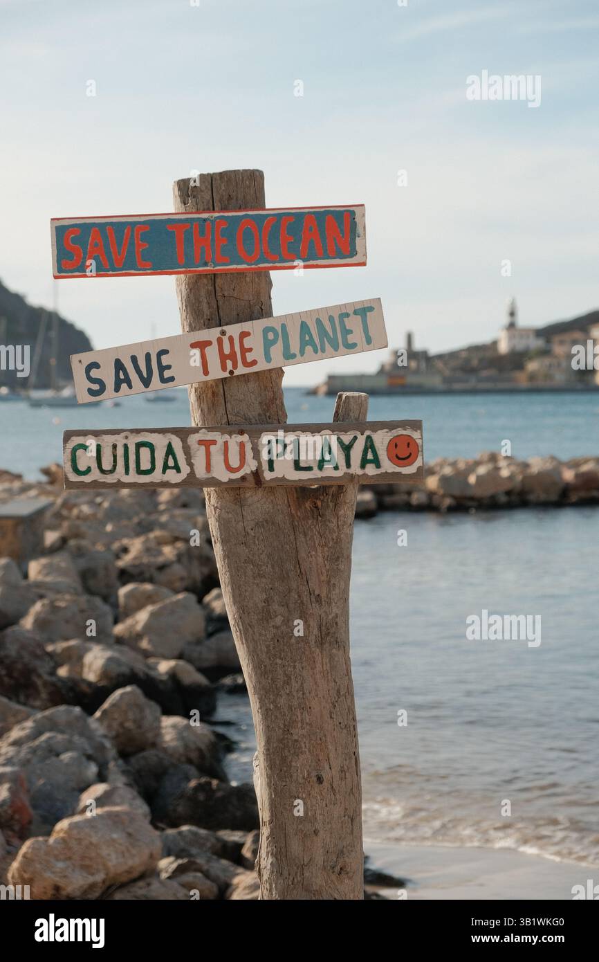 Holzschild mit Umweltschutz-Botschaften 'Save the Ocean', 'Save the Planet' und 'Cuida la Playa' an einer felsigen Küste mit Meerblick und einer klein. Banque D'Images