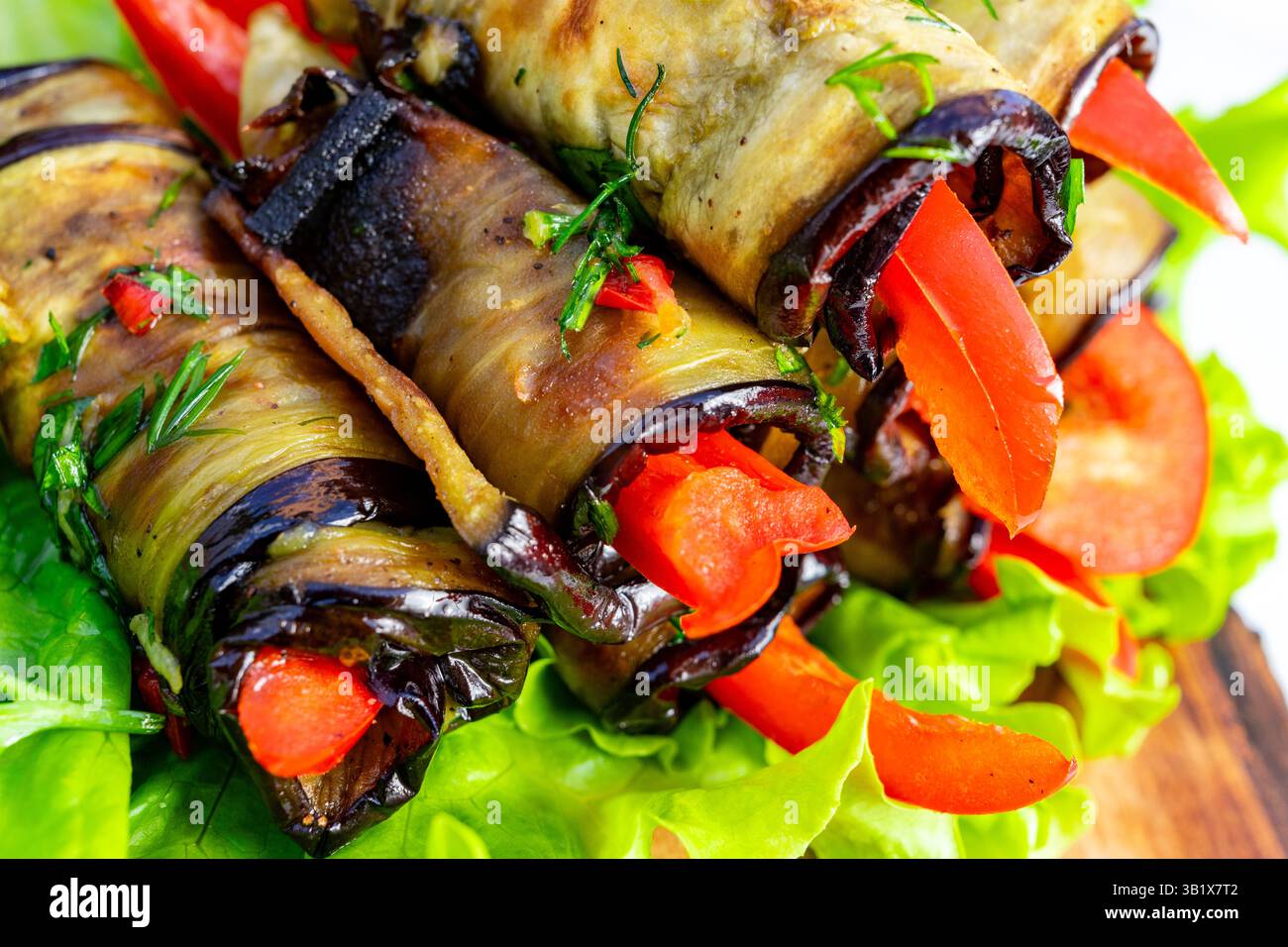 Des rouleaux de légumes grillés colorés remplis de poivrons frais et d'herbes sont assis sur un lit de laitue croustillante. Le plat offre une perfe de présentation vibrante Banque D'Images