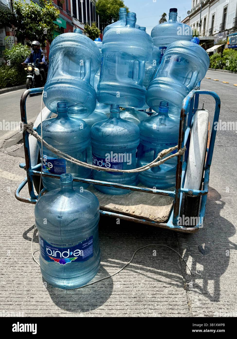 Beaucoup de gens dans la ville de Mexico considèrent encore que l'eau du robinet n'est pas potable. Par conséquent, les camions manuels à trois roues se déplacent dans les quartiers pour recueillir les vides et livrer des bouteilles d'eau pleines. Cela crée une mini économie pour de nombreux pauvres impliqués dans ce métier de distribution et permet le recyclage des grosses bouteilles en plastique qui sont renvoyées aux entreprises pour être nettoyées, désinfectées et rechargées professionnellement dans des normes d’hygiène strictes Banque D'Images