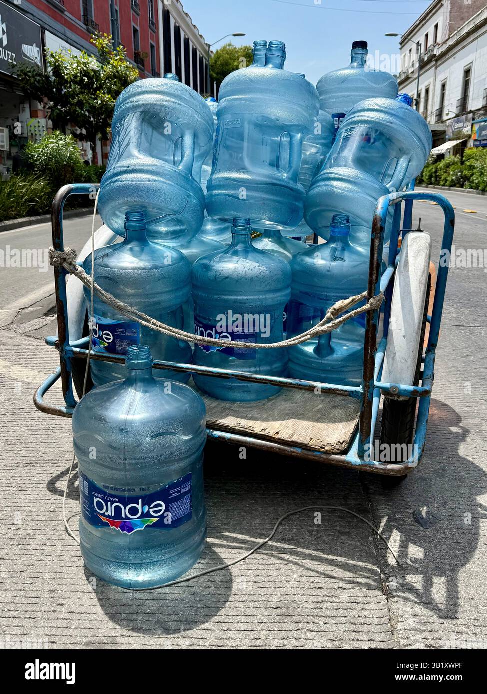 Beaucoup de gens dans la ville de Mexico considèrent encore que l'eau du robinet n'est pas potable. Par conséquent, les camions manuels à trois roues se déplacent dans les quartiers pour recueillir les vides et livrer des bouteilles d'eau pleines. Cela crée une mini économie pour de nombreux pauvres impliqués dans ce métier de distribution et permet le recyclage des grosses bouteilles en plastique qui sont renvoyées aux entreprises pour être nettoyées, désinfectées et rechargées professionnellement dans des normes d’hygiène strictes Banque D'Images
