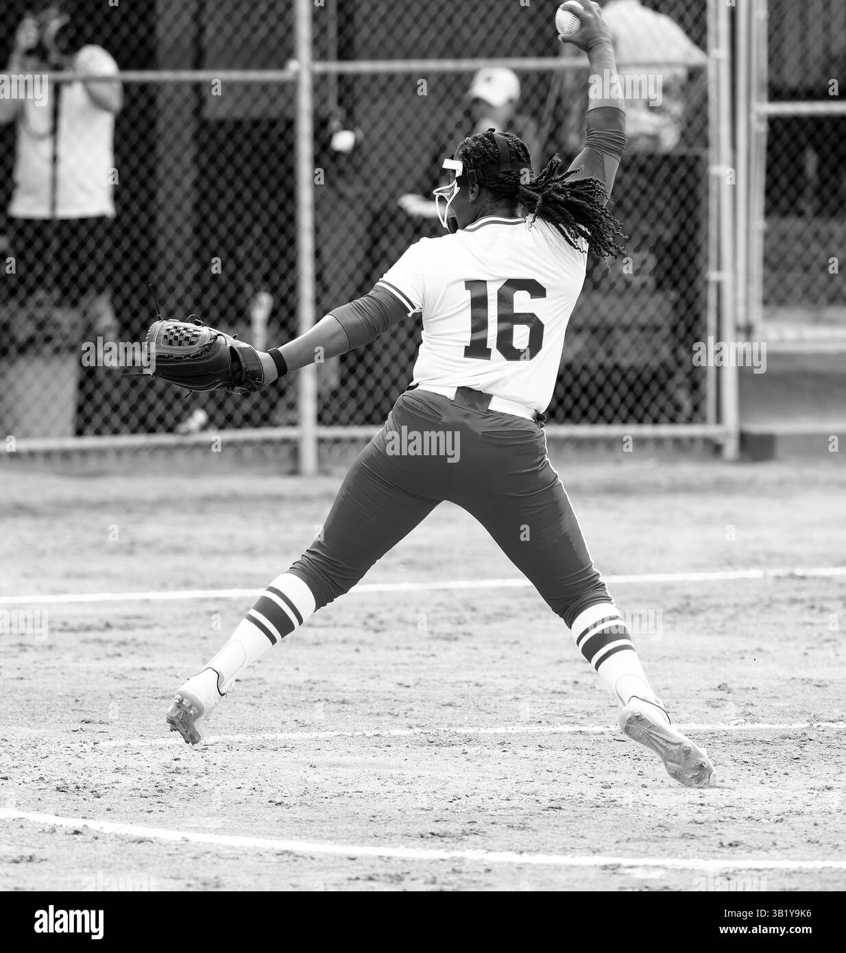 Un pichet de softball à pas rapide est en plein vent en lançant la balle à la plaque d'accueil noir et blanc vertical Banque D'Images