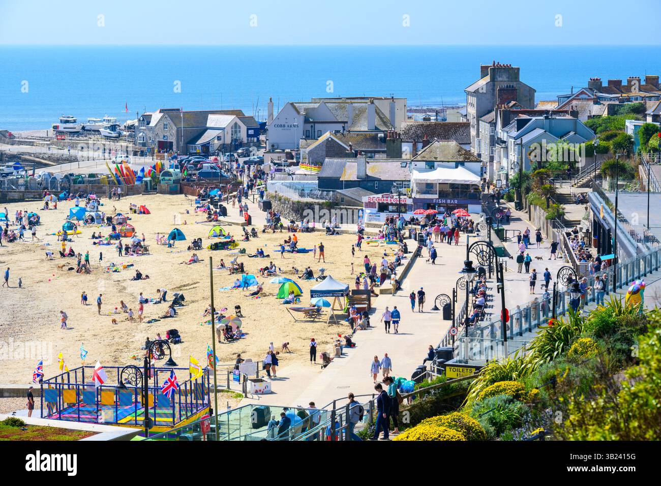 Lyme Regis, Dorset, Royaume-Uni. 27 avril 2025. Météo britannique : les voyageurs d'une journée et les habitants affluent à la plage de la pittoresque station balnéaire de Lyme Regis pour se prélasser sous un soleil brûlant le dimanche. Des conditions chaudes et ensoleillées sont prévues toute la semaine avec des températures fixées pour monter en flèche vers le week-end, lorsque le Royaume-Uni est susceptible de voir le jour le plus chaud de l'année jusqu'à présent. Crédit : Celia McMahon/Alamy Live News Banque D'Images
