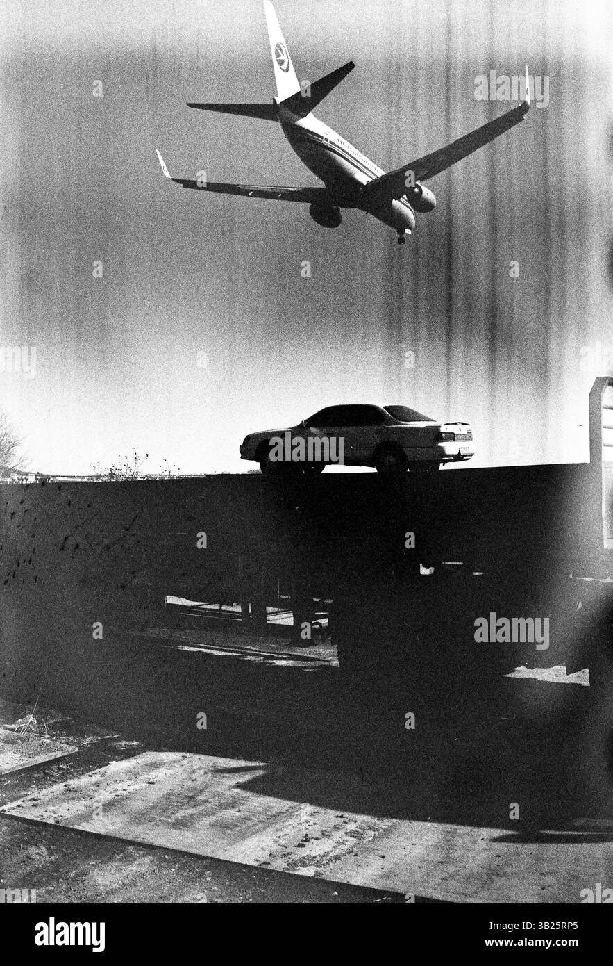 Vol à basse altitude China Eastern Airlines Boeing 737 avion et voiture statique à l'aéroport de Dalian, mouvement contrastant photographie noir et blanc, années 2010, Dalian, Liaoning, Chine Banque D'Images