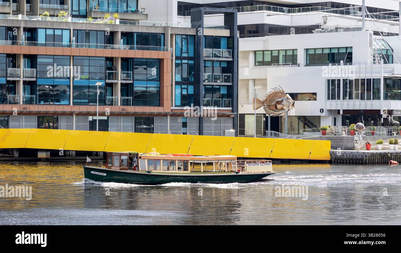 Melbourne, Australie - 21 janvier 2023 : bateau de plaisance sur la rivière Yarra avec cafés et restaurants sur le WTC Wharf derrière. La sculpture de poisson John Dory Banque D'Images