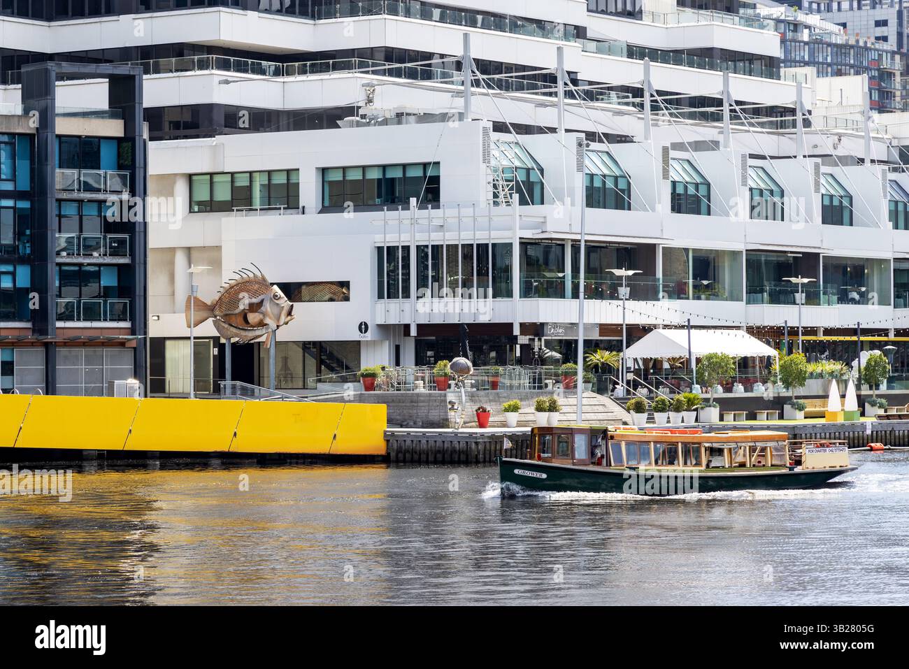 Melbourne, Australie - 21 janvier 2023 : bateau de plaisance sur la rivière Yarra avec cafés et restaurants sur le WTC Wharf derrière. La sculpture de poisson John Dory Banque D'Images