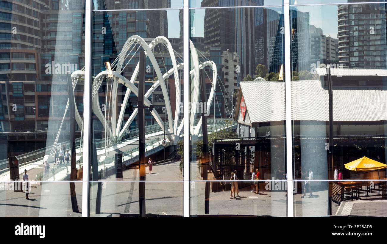 Melbourne, Australie - 21 janvier 2023 : le pont moderne des marins sur la rivière Yarra, reflété par la façade vitrée d'un bâtiment à côté. Été vi Banque D'Images