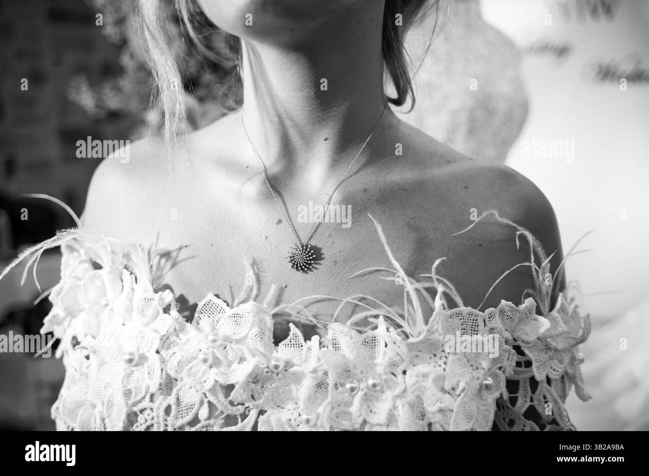 Image en gros plan noir et blanc d'une mariée portant une robe en dentelle délicate et un collier complexe. Concentrez-vous sur la tenue de mariée élégante et les bijoux fins Banque D'Images