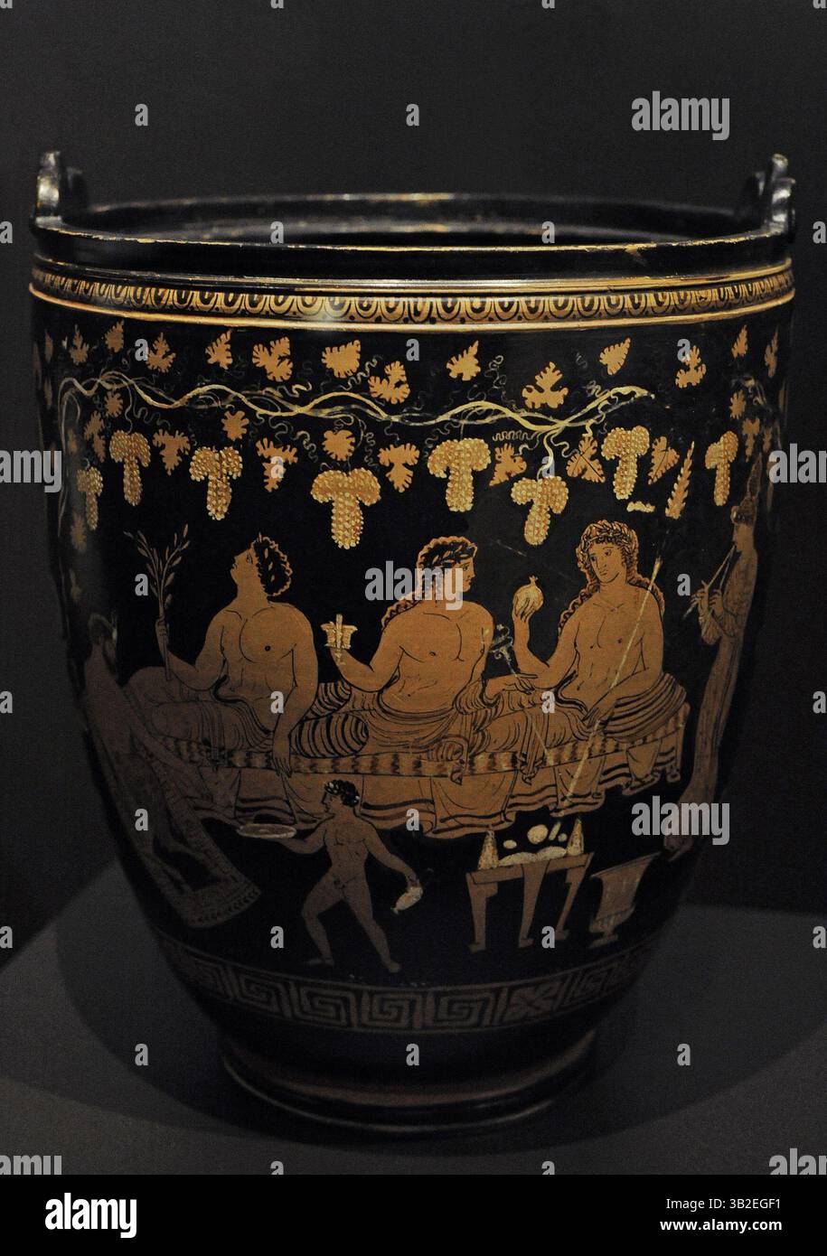 Situla avec scène représentant un symposium. Trois participants se sont couchés sur un seul canapé. De gauche à droite : Apollon tenant une branche de laurier tout en levant la tête vers le haut ; Hermès tenant le caducée dans une main ; Dionysos tenant dans sa main droite la grenade, fruit de l'immortalité. Argile. 350-330 AV. J.-C. Groupe des situlae de Dublin. Depuis les Pouilles, Italie. Musée archéologique national. Madrid. Espagne. Banque D'Images