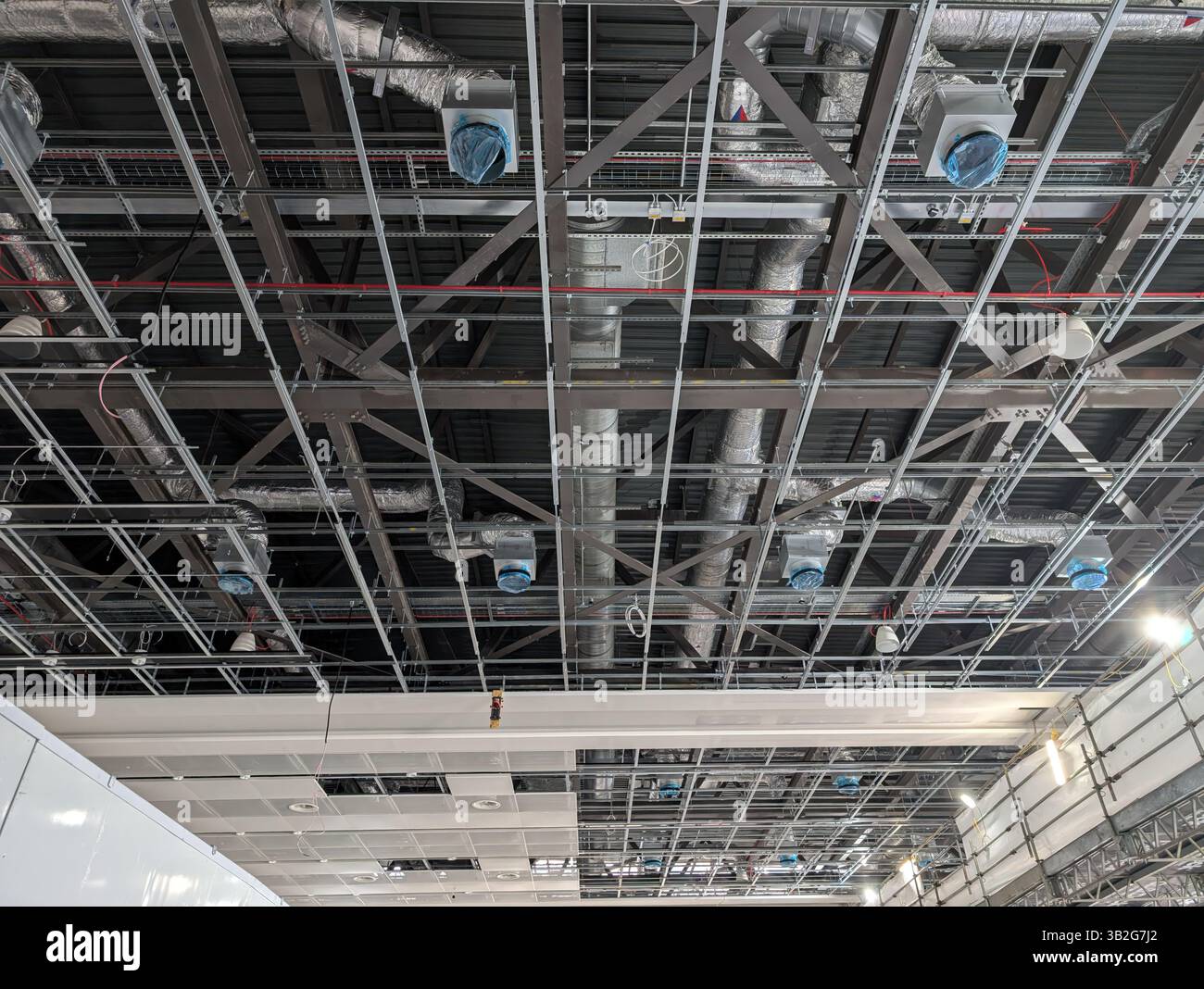 Plafond exposé industriel en construction, avec gaines HVAC, câblage électrique, tuyauterie et cadre de grille de plafond suspendu. L'image sho Banque D'Images