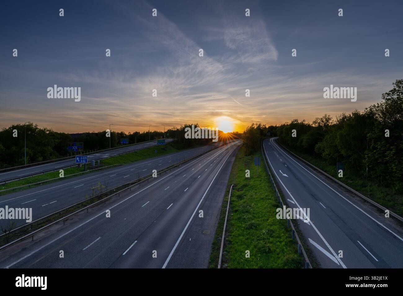 Vue imprenable sur une autoroute vide pendant un coucher de soleil vibrant, avec un ciel coloré et une atmosphère paisible Banque D'Images