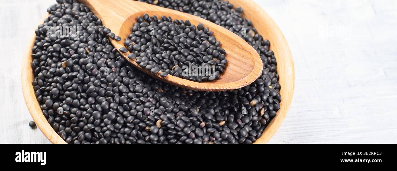 Graines de lentilles de béluga noir sur fond blanc. Vue de dessus. Panorama avec espace de copie. Banque D'Images