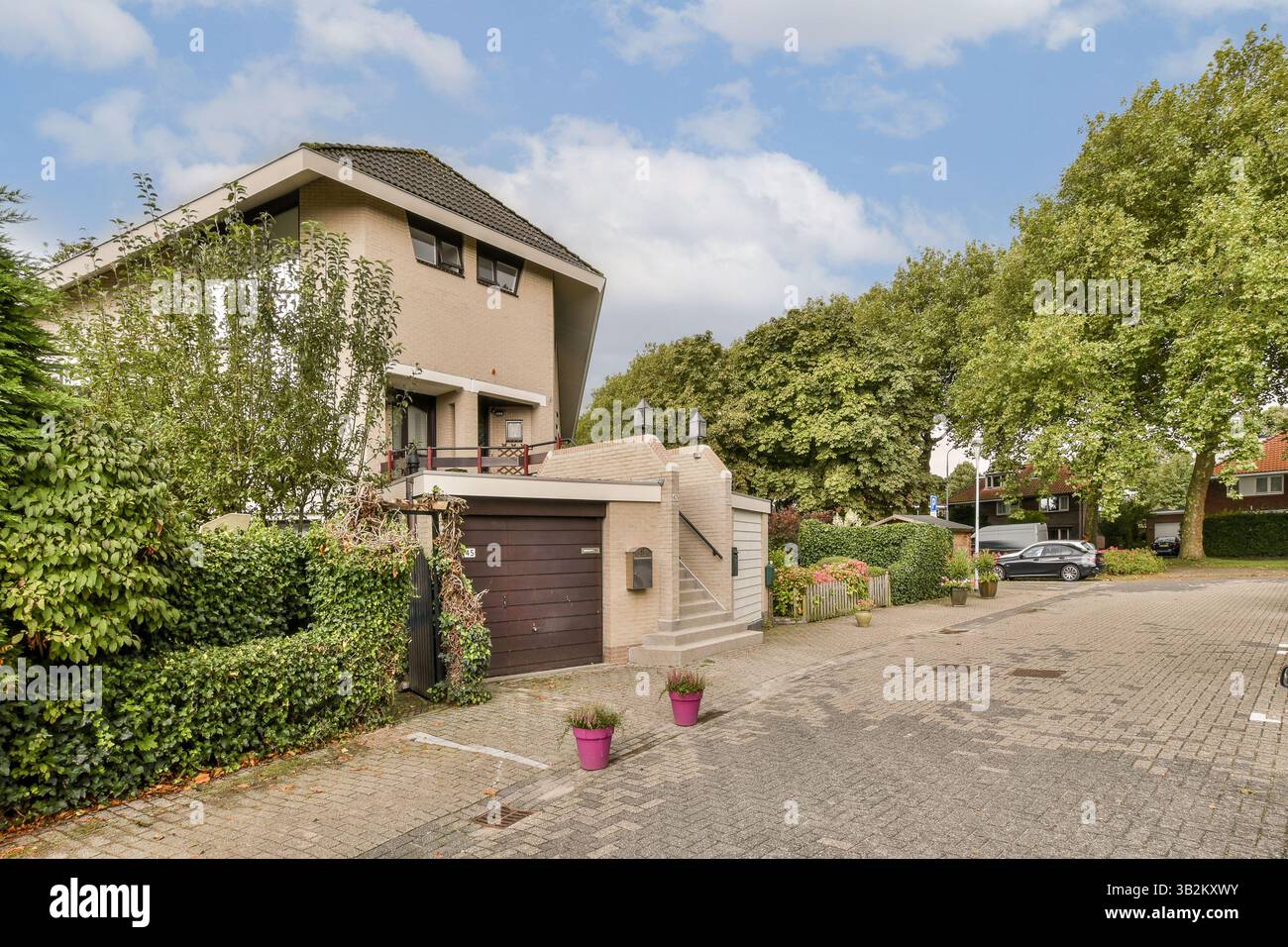 Une maison contemporaine avec un jardin et une allée bien entretenus, situé dans un quartier serein de banlieue avec une végétation luxuriante. Banque D'Images