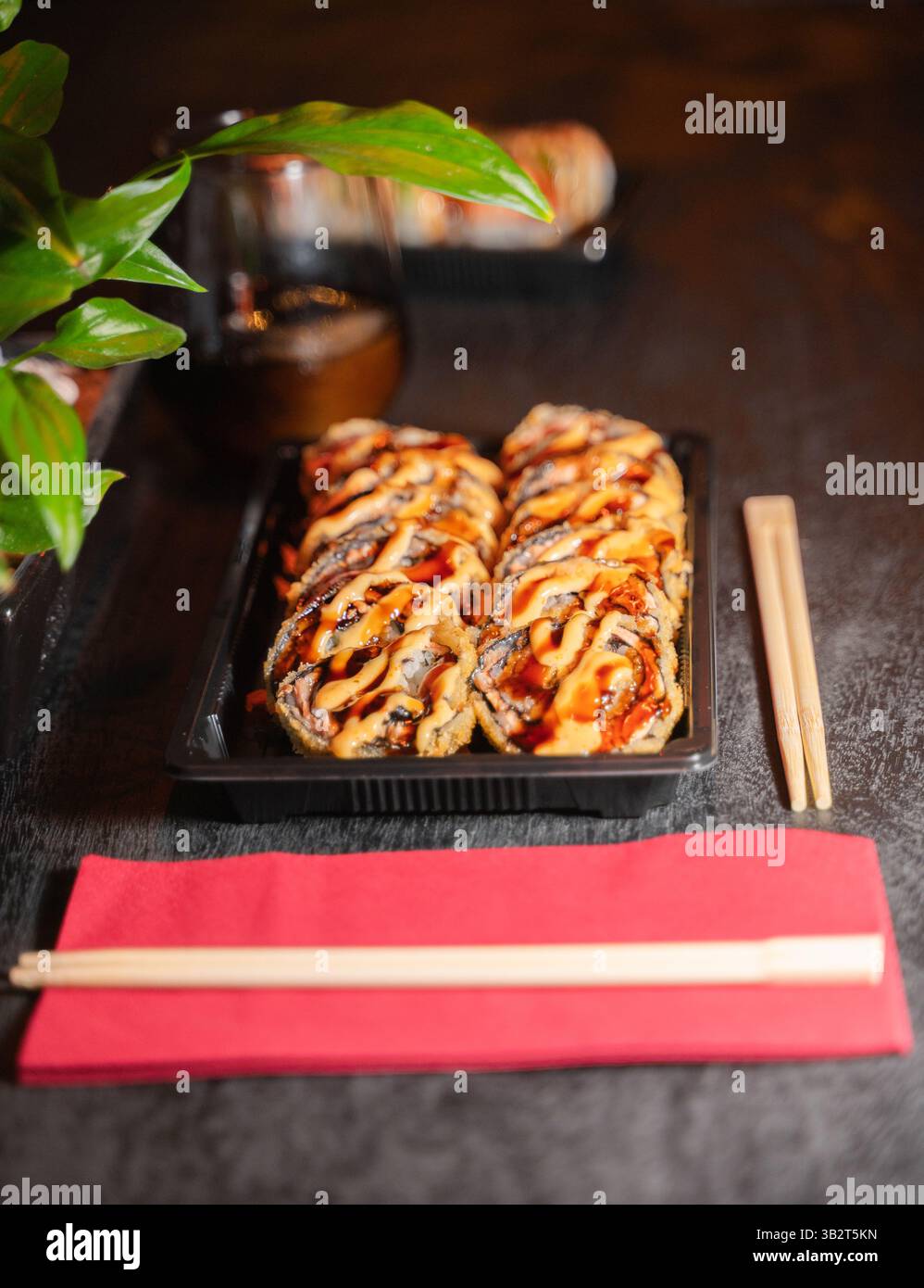 Un plateau de sushis magnifiquement arrangé accompagné de baguettes et d'une serviette rouge éclatante, habilement placé sur une table en bois Banque D'Images