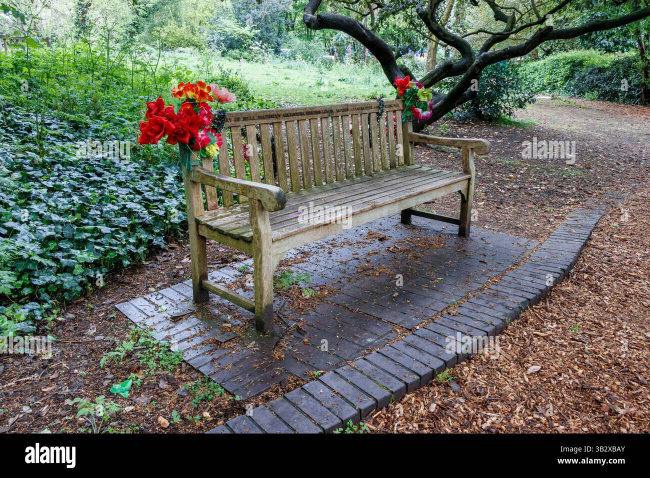 Un hommage floral sur un banc commémoratif dans Sunnyside Gardens, une réserve naturelle publique dans le nord de Londres, Royaume-Uni Banque D'Images